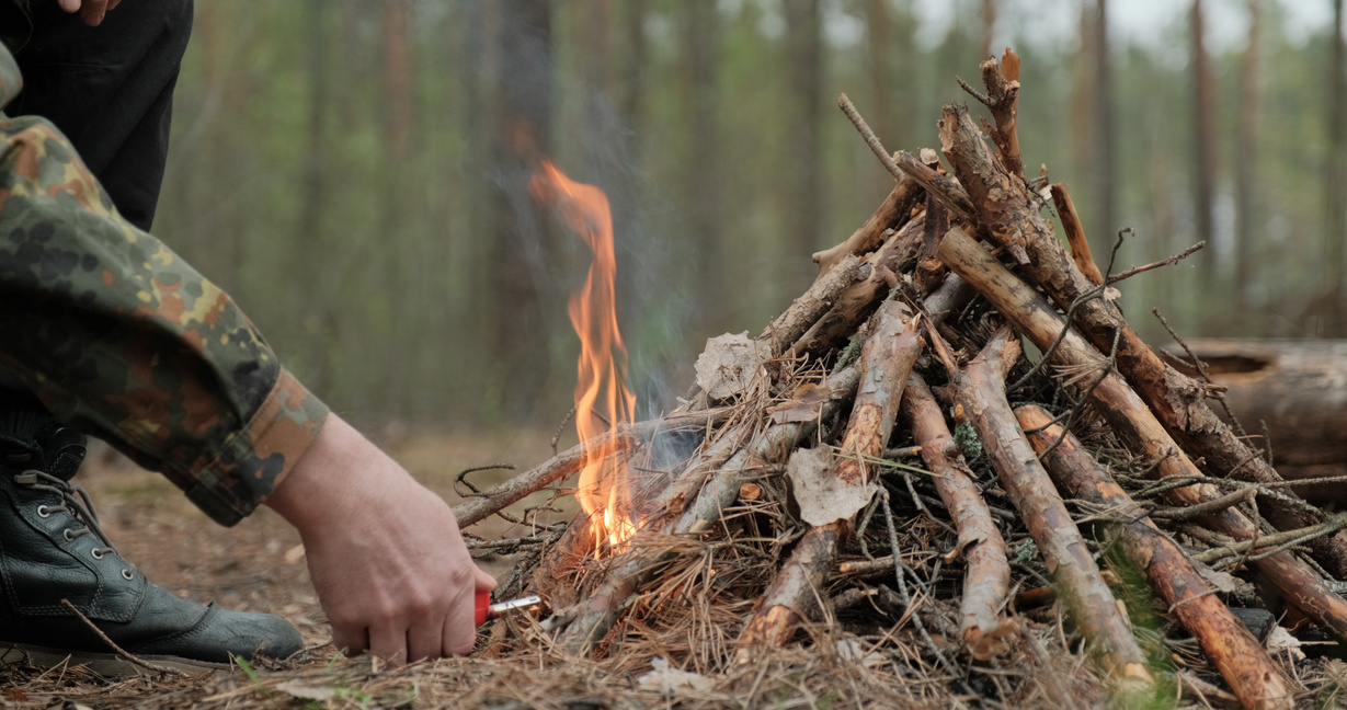 Man Starts a Fire in the Forest Using a Lighter. Close-up of a M